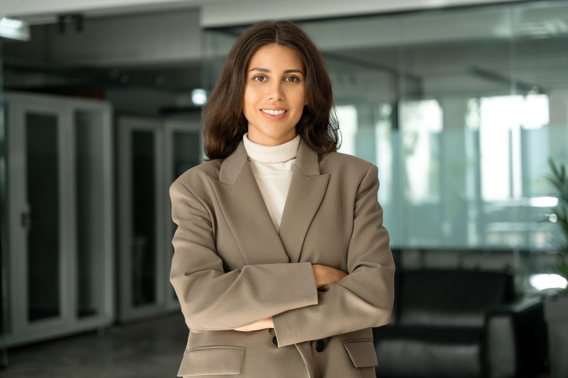 Portrait of beautiful successful hispanic young business woman with crossed arms smiling at camera. Latin or eastern confident middle age female ceo leader businesswoman standing in office. Copy space
