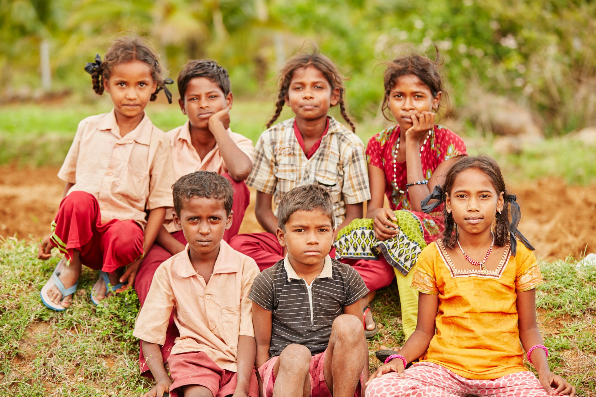 Group of cheerful teen village friends sitting on farm land
